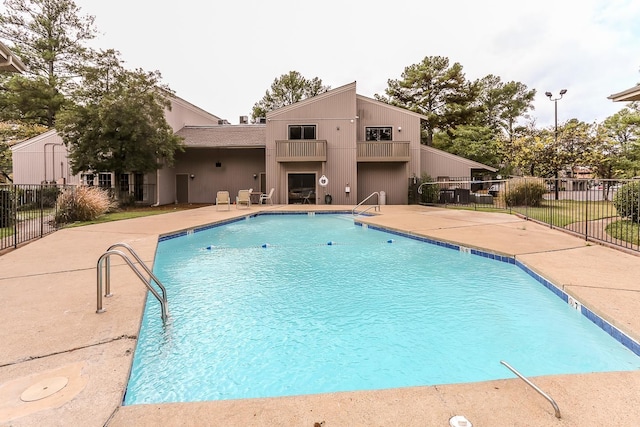 community pool with a patio and fence