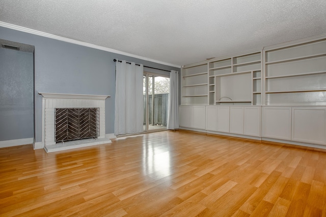 unfurnished living room featuring a textured ceiling, visible vents, ornamental molding, a brick fireplace, and light wood finished floors