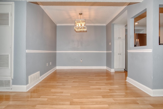 spare room featuring light wood-type flooring, visible vents, and crown molding