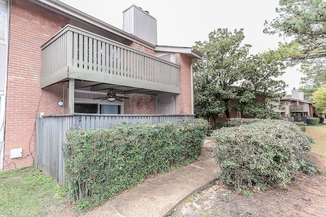 view of side of property with brick siding, a chimney, and a balcony