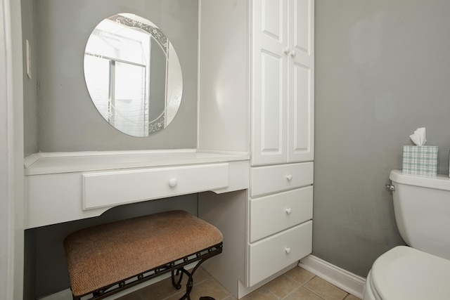 half bathroom featuring tile patterned flooring, toilet, and baseboards