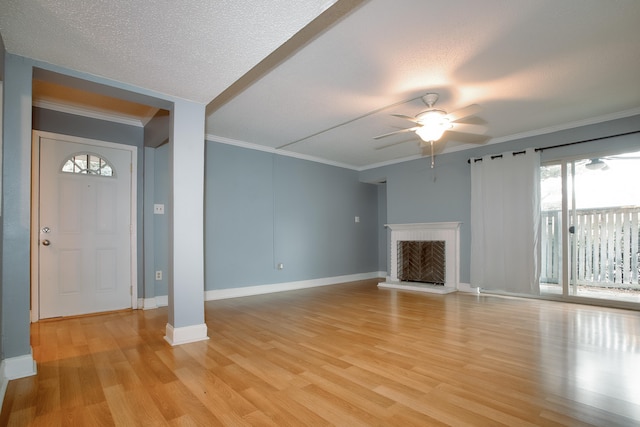 unfurnished living room featuring ceiling fan, light wood-type flooring, a brick fireplace, and crown molding