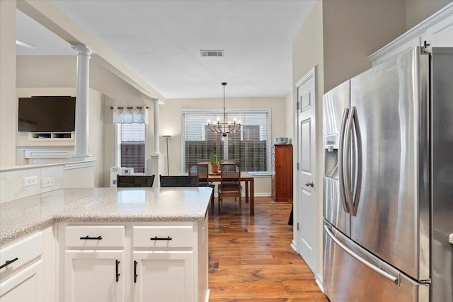 kitchen with visible vents, stainless steel fridge with ice dispenser, light wood-style flooring, ornate columns, and white cabinetry