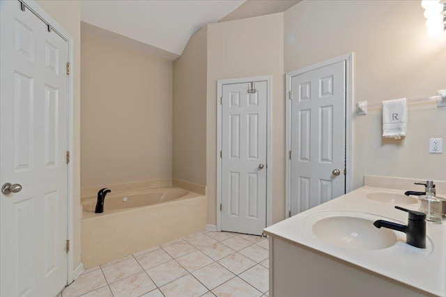 bathroom featuring lofted ceiling, tile patterned flooring, a sink, and a bath