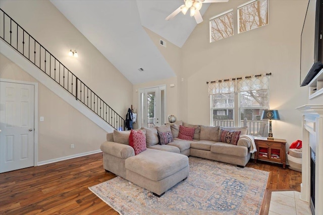 living area featuring a fireplace with flush hearth, stairs, visible vents, and wood finished floors