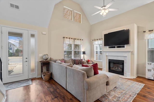 living area featuring baseboards, visible vents, wood finished floors, a fireplace, and high vaulted ceiling