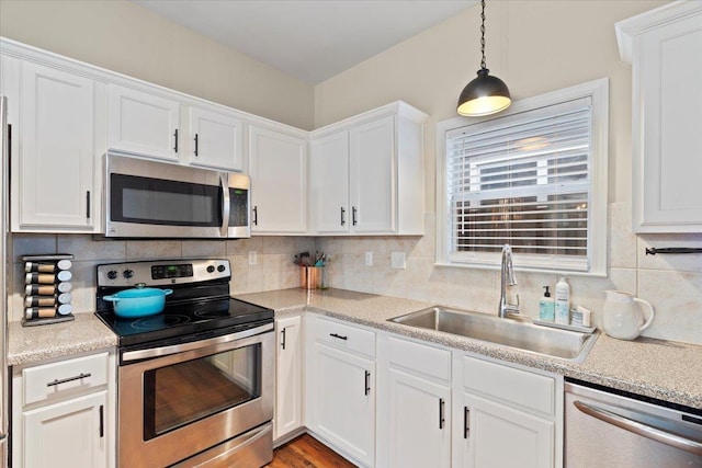 kitchen with appliances with stainless steel finishes, backsplash, a sink, and white cabinetry