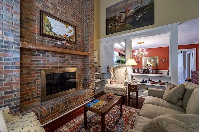 living area featuring crown molding, a brick fireplace, a notable chandelier, and wood finished floors