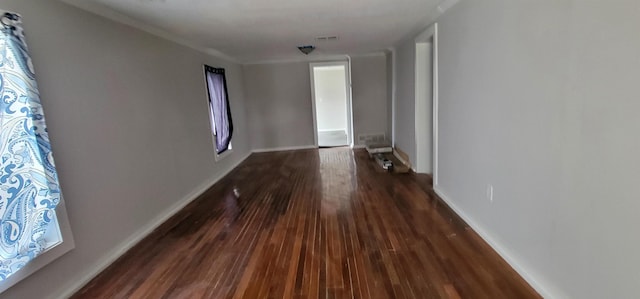 hall with dark wood-style flooring, visible vents, and baseboards