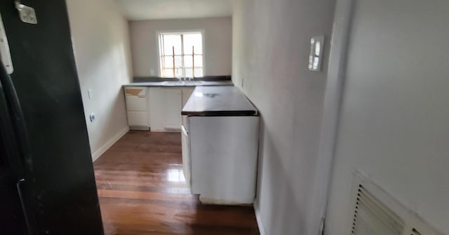 interior space featuring baseboards, white cabinets, and wood finished floors