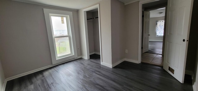 unfurnished bedroom featuring dark wood-type flooring, a closet, and baseboards