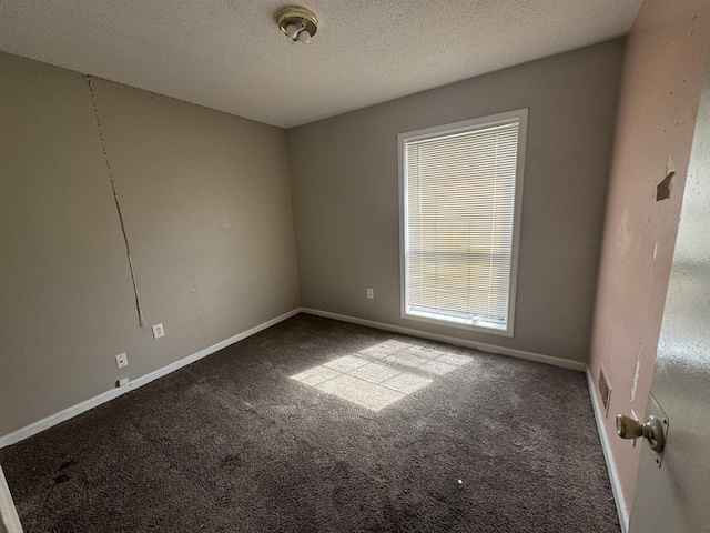 carpeted empty room featuring visible vents, a textured ceiling, and baseboards