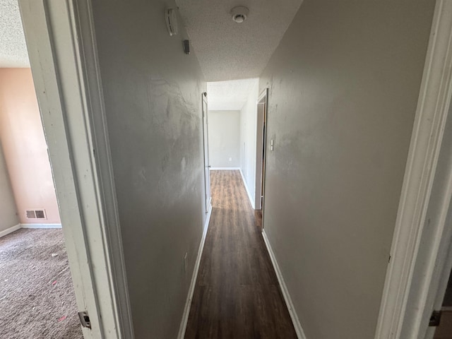 corridor with a textured ceiling and baseboards