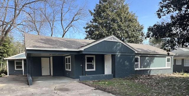 single story home featuring concrete driveway, brick siding, a shingled roof, and an attached carport