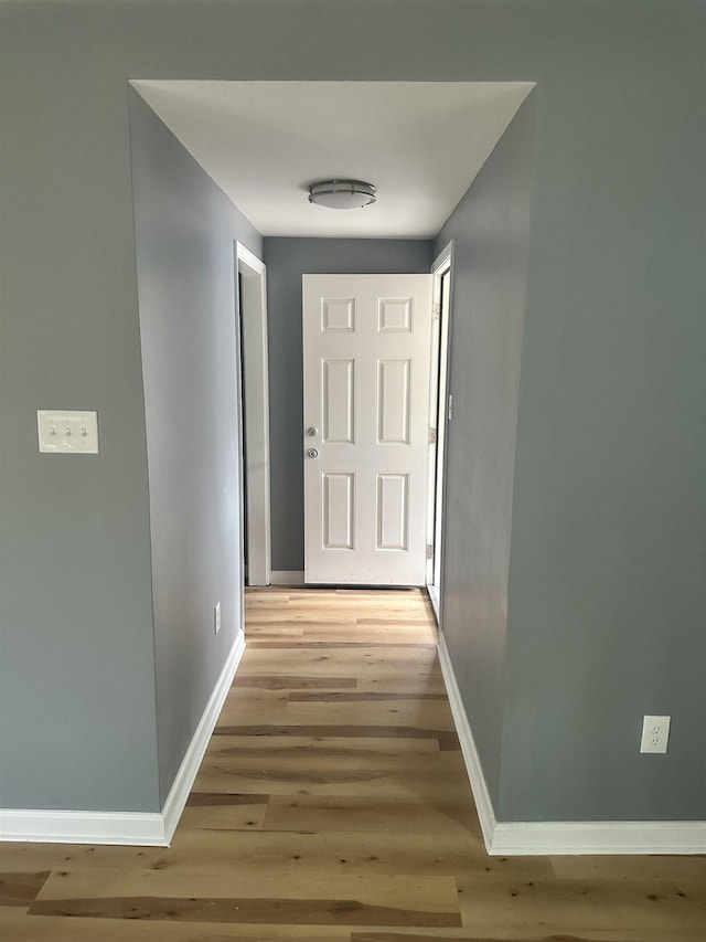 corridor featuring light wood finished floors and baseboards