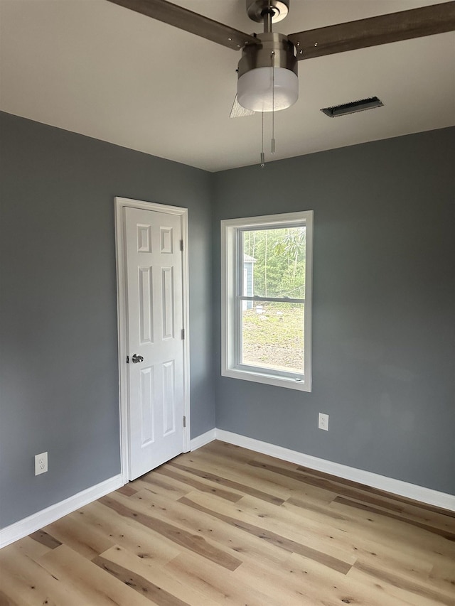 spare room featuring visible vents, light wood-style flooring, and baseboards