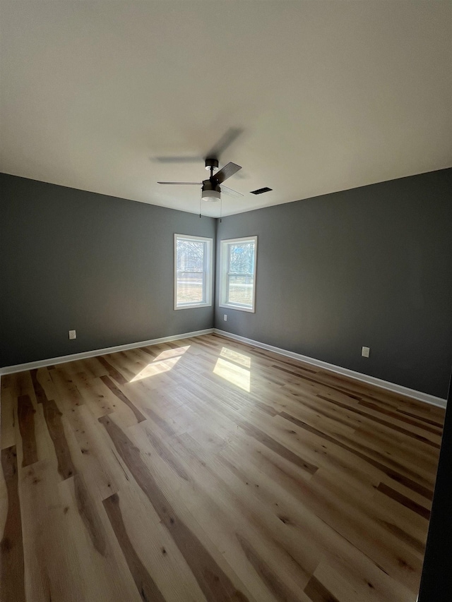 unfurnished room with ceiling fan, wood finished floors, and baseboards