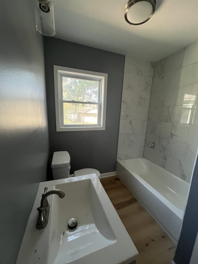 bathroom featuring toilet, a sink, baseboards, and wood finished floors