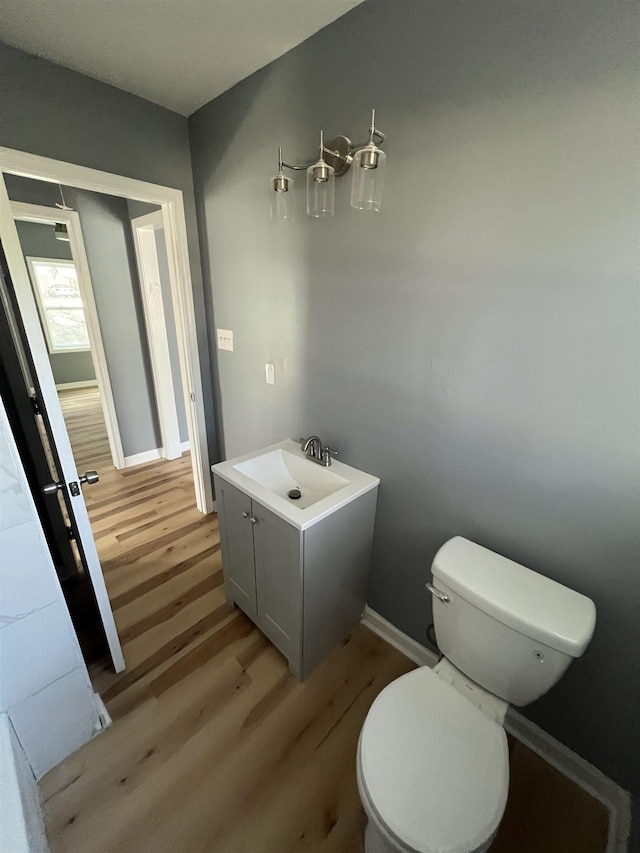 bathroom with toilet, baseboards, a sink, and wood finished floors