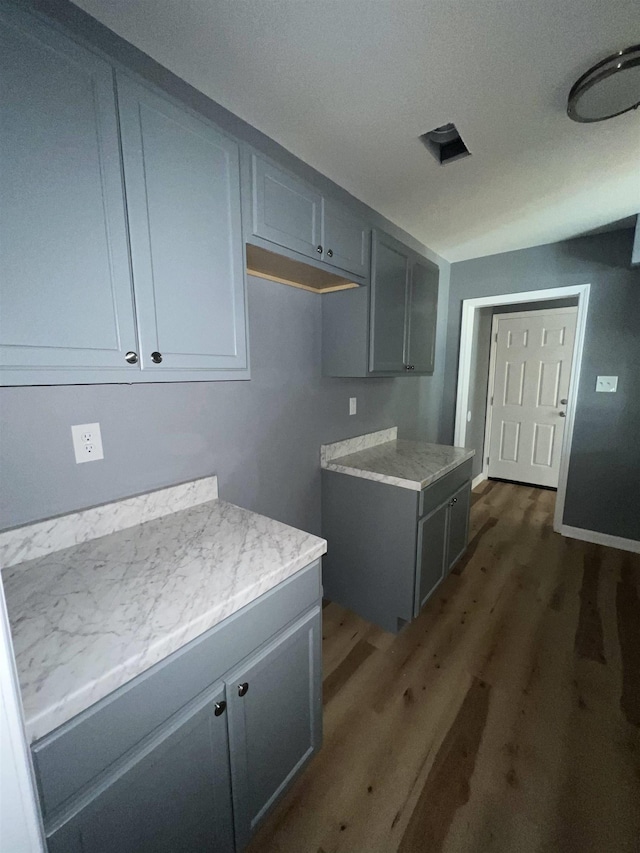 kitchen with baseboards, light countertops, wood finished floors, and gray cabinetry