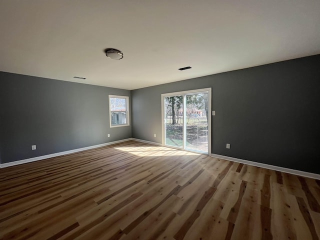 unfurnished room with wood finished floors, visible vents, and baseboards