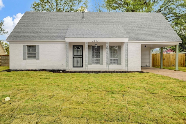 view of front of home with brick siding, concrete driveway, fence, an attached carport, and a front lawn