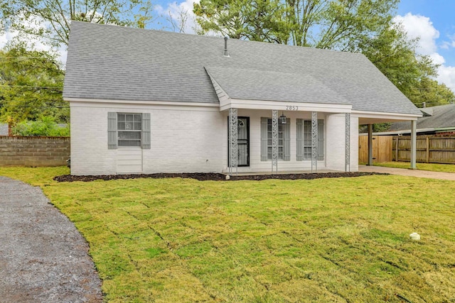 view of front of home with a shingled roof, concrete driveway, fence, a front lawn, and brick siding