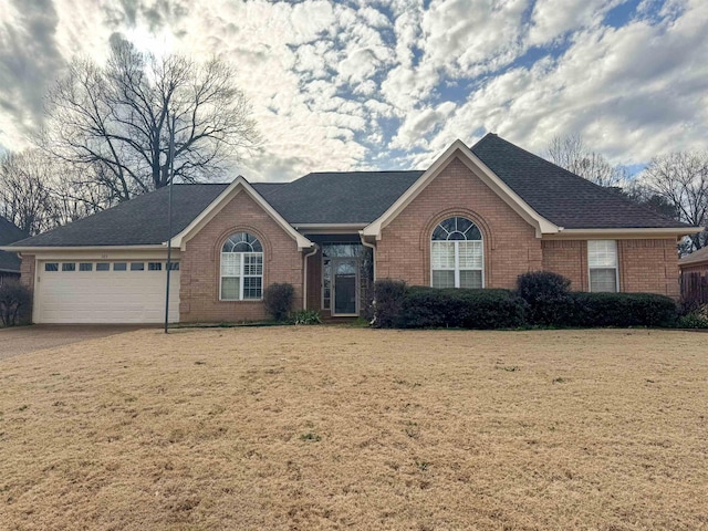 ranch-style house featuring a garage, brick siding, a front lawn, and roof with shingles