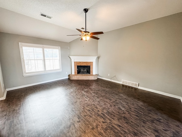 unfurnished living room with dark wood-style floors, a brick fireplace, visible vents, and vaulted ceiling