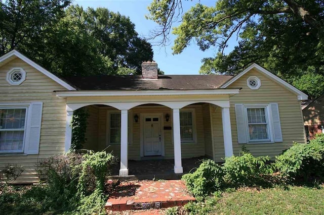 view of front facade featuring a porch and a chimney