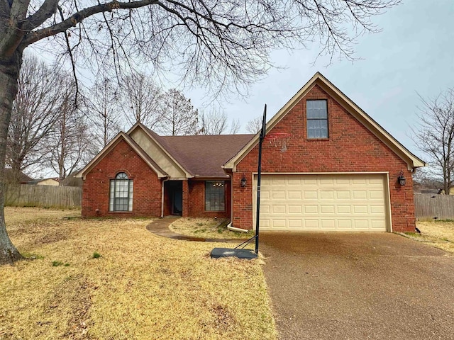 traditional-style home featuring a garage, concrete driveway, brick siding, and fence