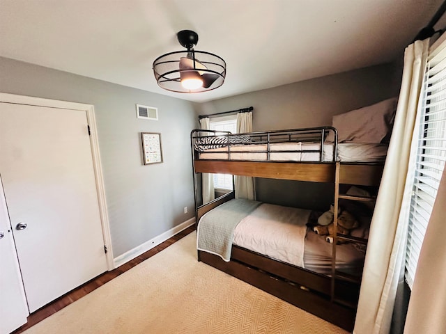 bedroom with wood finished floors, visible vents, and baseboards