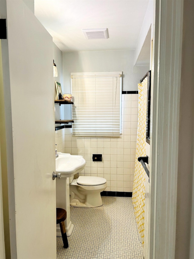 bathroom with visible vents, curtained shower, toilet, tile patterned floors, and tile walls