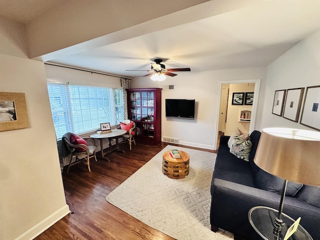 living area with a ceiling fan, wood finished floors, visible vents, and baseboards