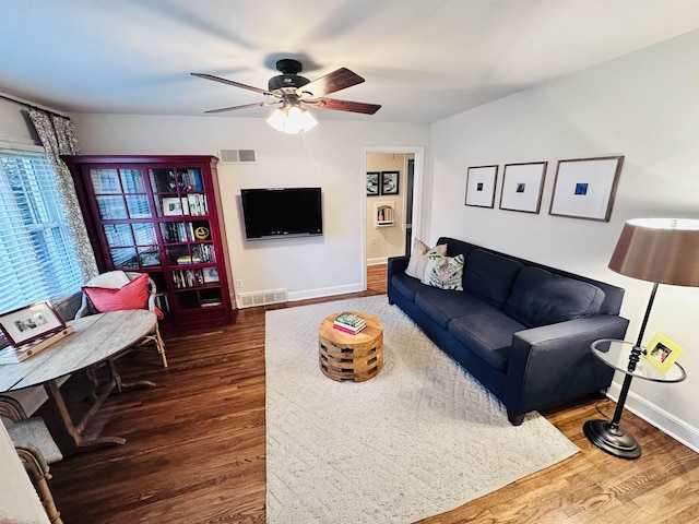 living area with ceiling fan, visible vents, baseboards, and wood finished floors