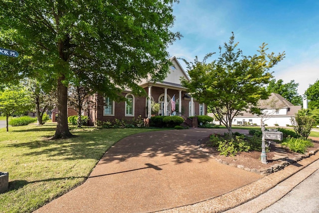 greek revival house featuring brick siding, a front yard, and driveway