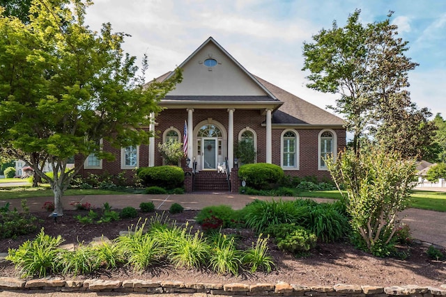 neoclassical / greek revival house featuring brick siding and a shingled roof