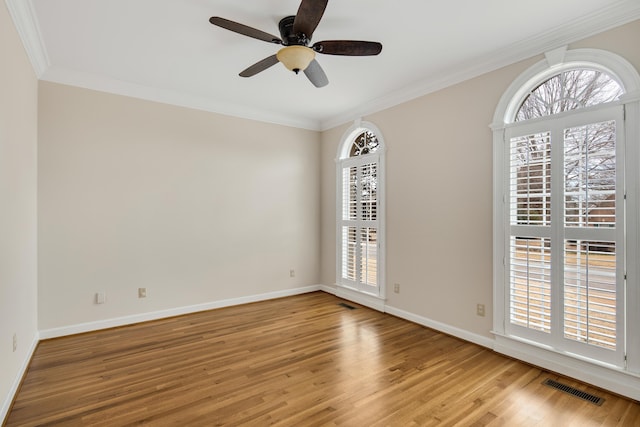 spare room with a healthy amount of sunlight, light wood-style floors, visible vents, and ornamental molding