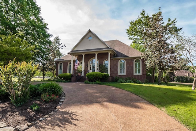 greek revival house with brick siding, concrete driveway, and a front yard