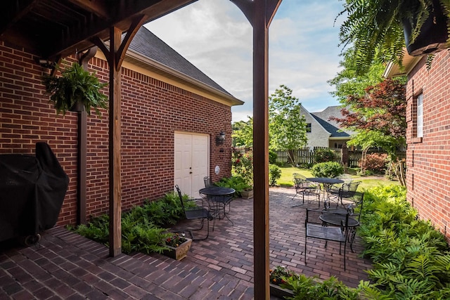 view of patio featuring grilling area, outdoor dining area, and fence