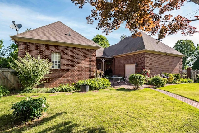 rear view of house featuring fence, a patio area, brick siding, and a lawn