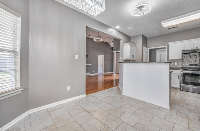 kitchen with dark stone countertops, visible vents, electric range, under cabinet range hood, and white cabinetry