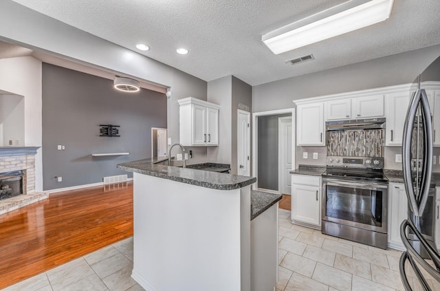 kitchen with electric stove, under cabinet range hood, fridge, white cabinets, and light tile patterned floors