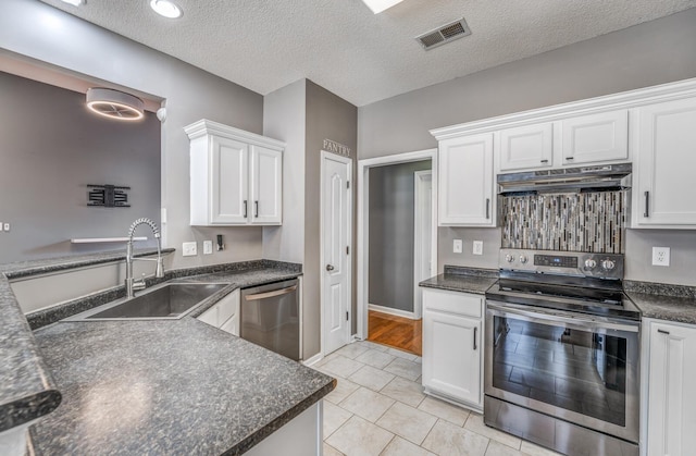 kitchen with visible vents, under cabinet range hood, a sink, dark countertops, and appliances with stainless steel finishes