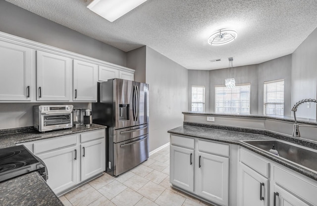 kitchen with a sink, dark countertops, and stainless steel fridge with ice dispenser