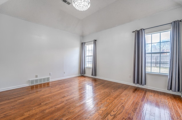 unfurnished room featuring visible vents, baseboards, an inviting chandelier, and hardwood / wood-style floors