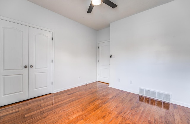 unfurnished bedroom with visible vents, wood finished floors, a closet, baseboards, and ceiling fan