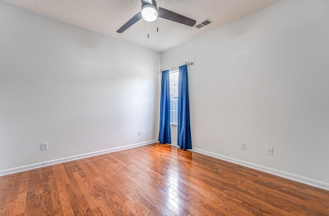 empty room with visible vents, a textured ceiling, a ceiling fan, and hardwood / wood-style flooring