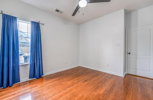 empty room with baseboards, wood finished floors, visible vents, and ceiling fan