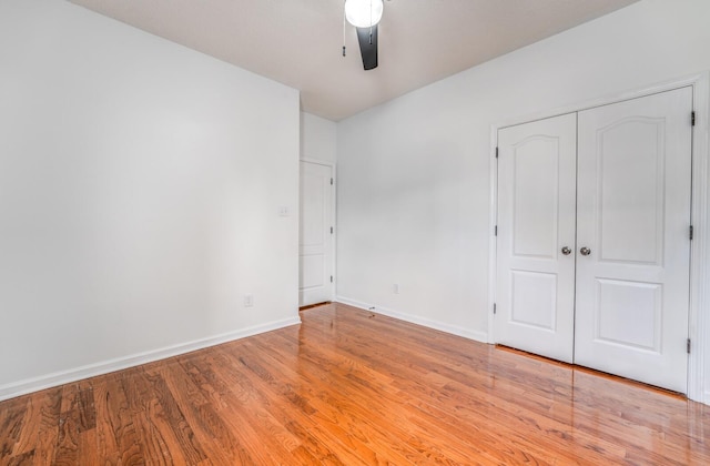 unfurnished bedroom featuring a closet, baseboards, light wood-style floors, and a ceiling fan